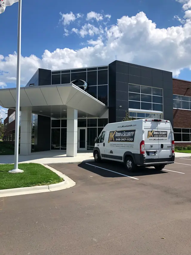 A JK Locksmith Co. service van parked outside a building entrance